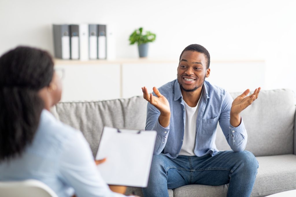 Successful therapy. Happy young black guy speaking to his psychologist, grateful for professional
